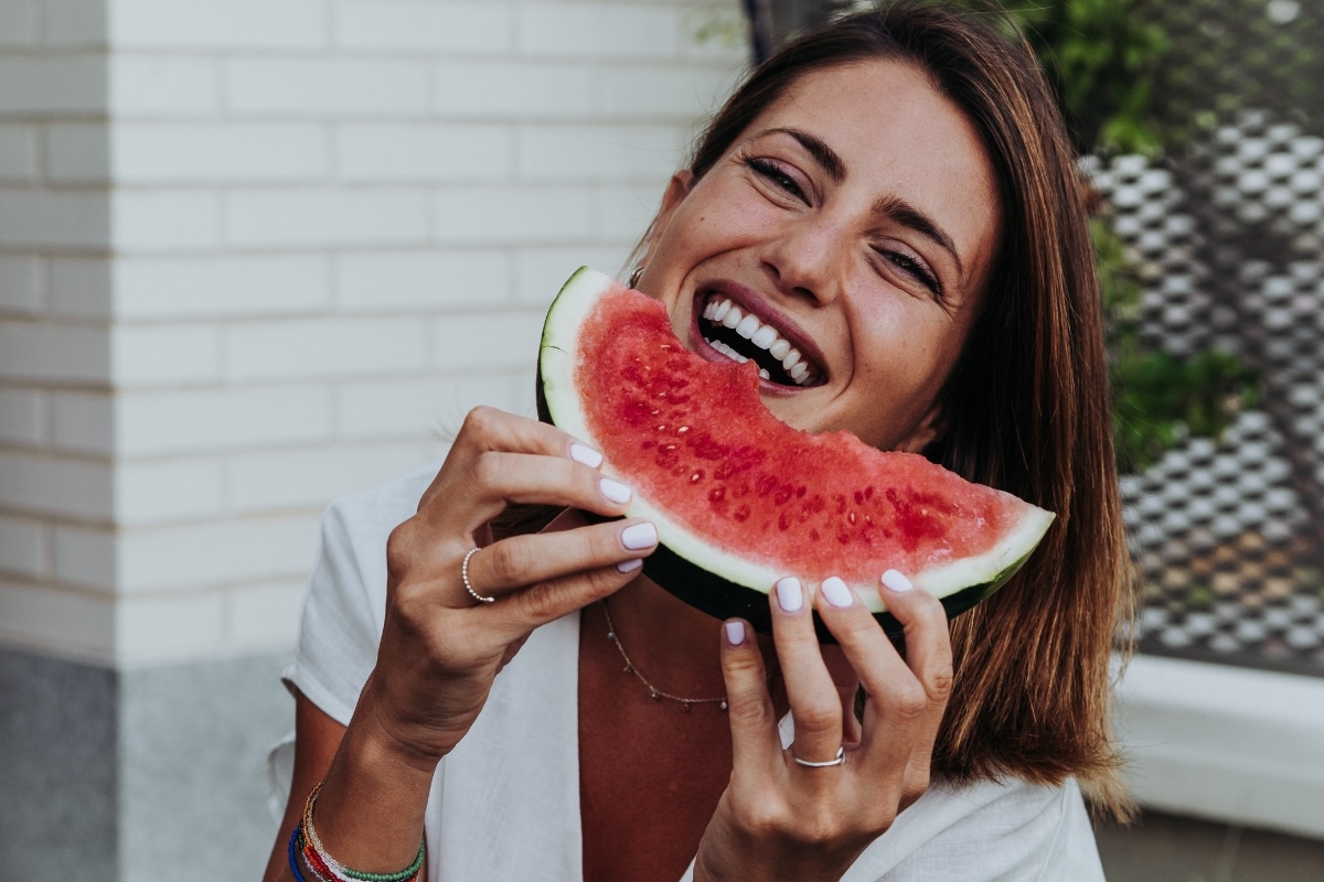 Woman enjoying watermelon after receiving dental implants in Austin