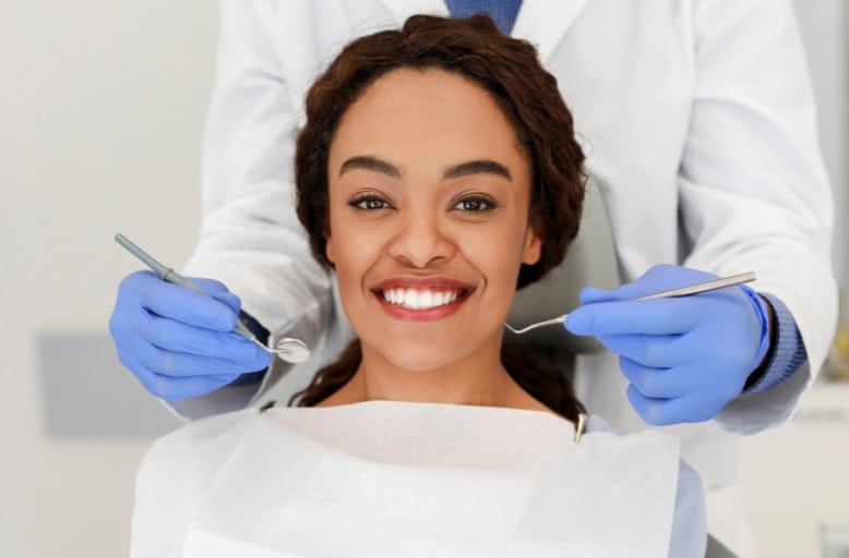 Smiling patient during dental exam at Daylight Dental in Austin TX with dentist holding dental tools