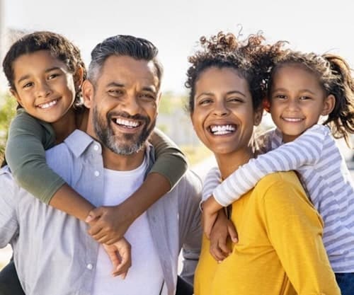 Happy family smiling with healthy, confident smiles after dental crown treatment in South Austin