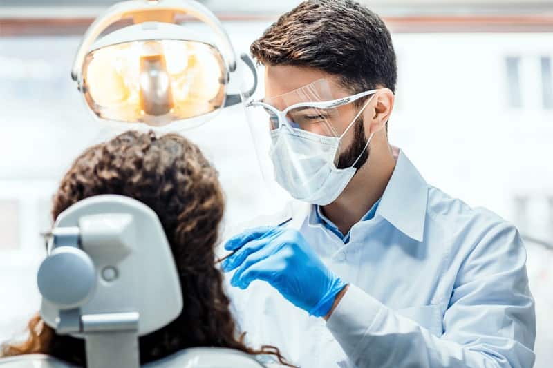 General dentist in South Austin performing a dental checkup on a patient using modern equipment in a clean and professional clinic.