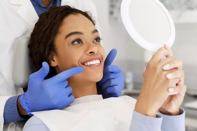 General dentist in South Austin evaluating patient teeth with mirror during routine dental exam in modern clinic