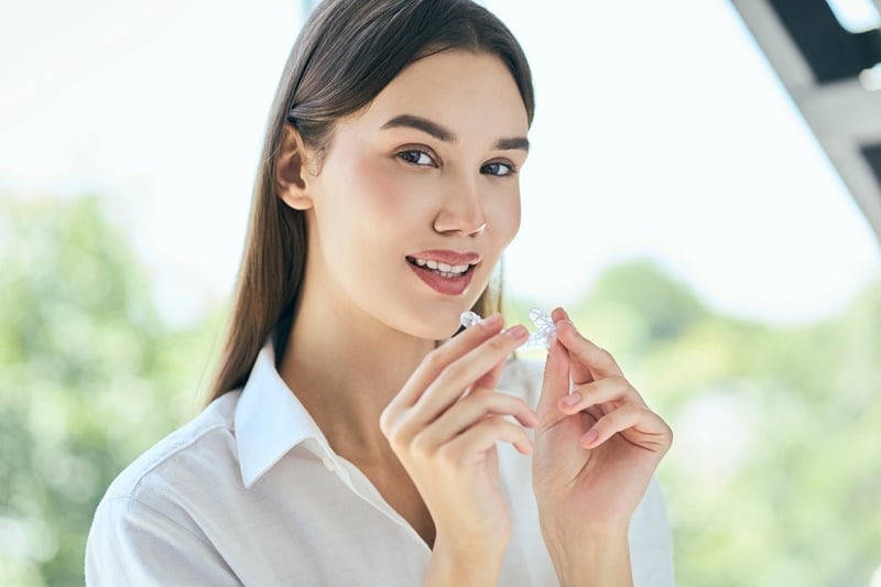 Young woman holding Invisalign clear aligners during a cosmetic dental consultation at Daylight Dental South Austin.