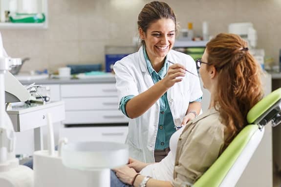 Dentist performing dental exam and cleaning for patient in South Austin clinic chair during routine checkup